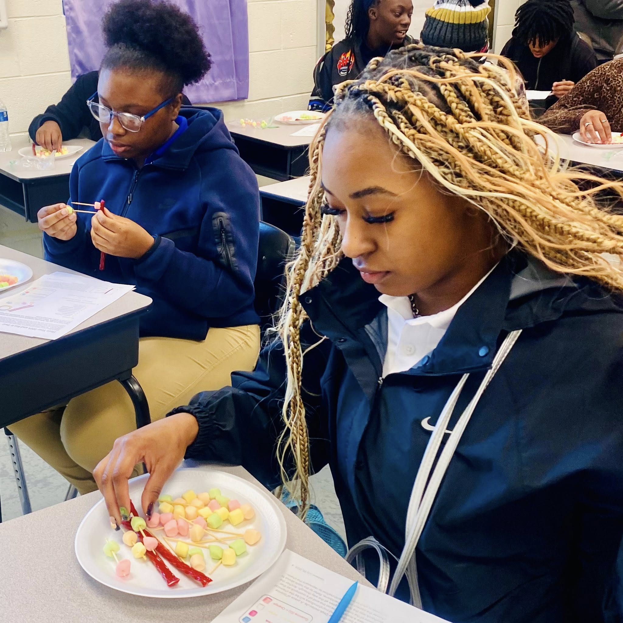 A girl looking at a plate with Twizzlers and mini marshmallows on it.